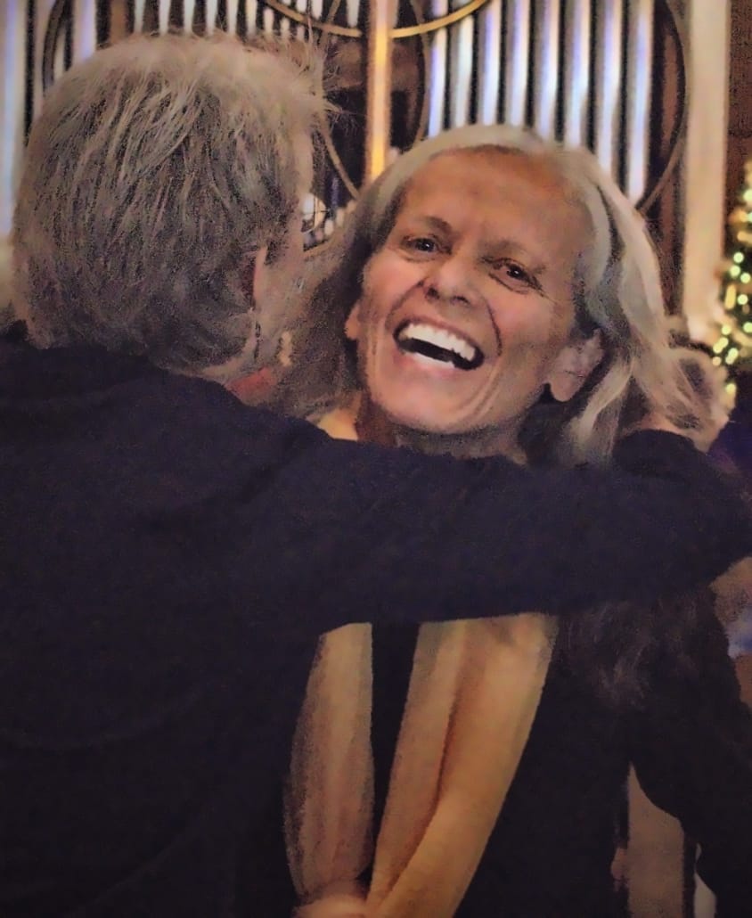 A Tucson Women's Chorus singer laughing as she embraces a friend after a performance